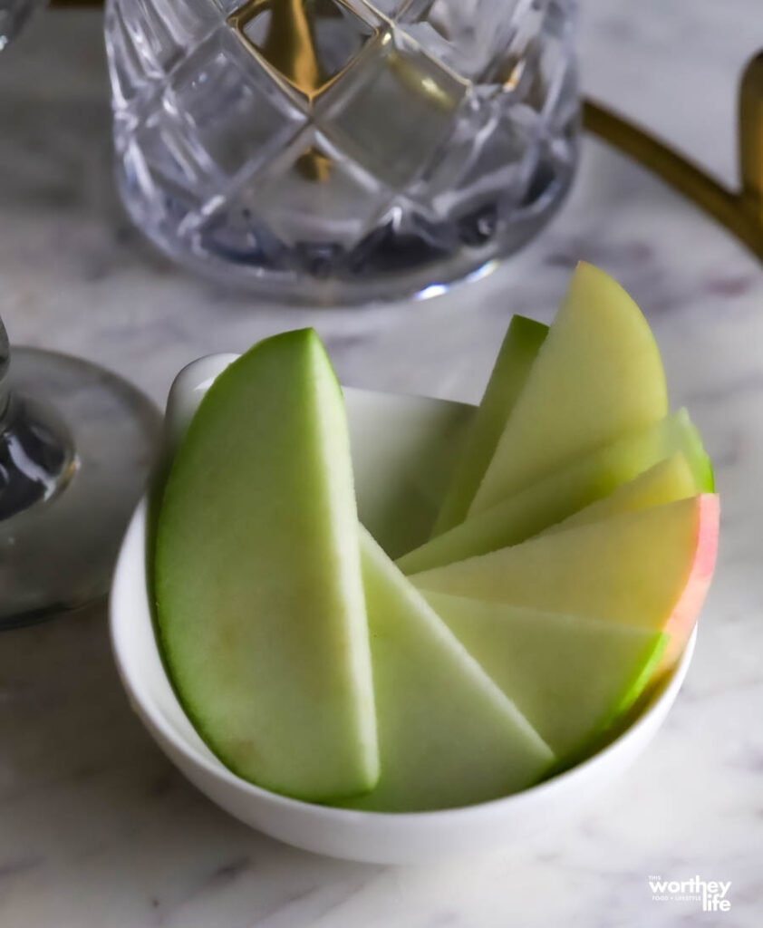 Sliced green apples in white bowl on white background