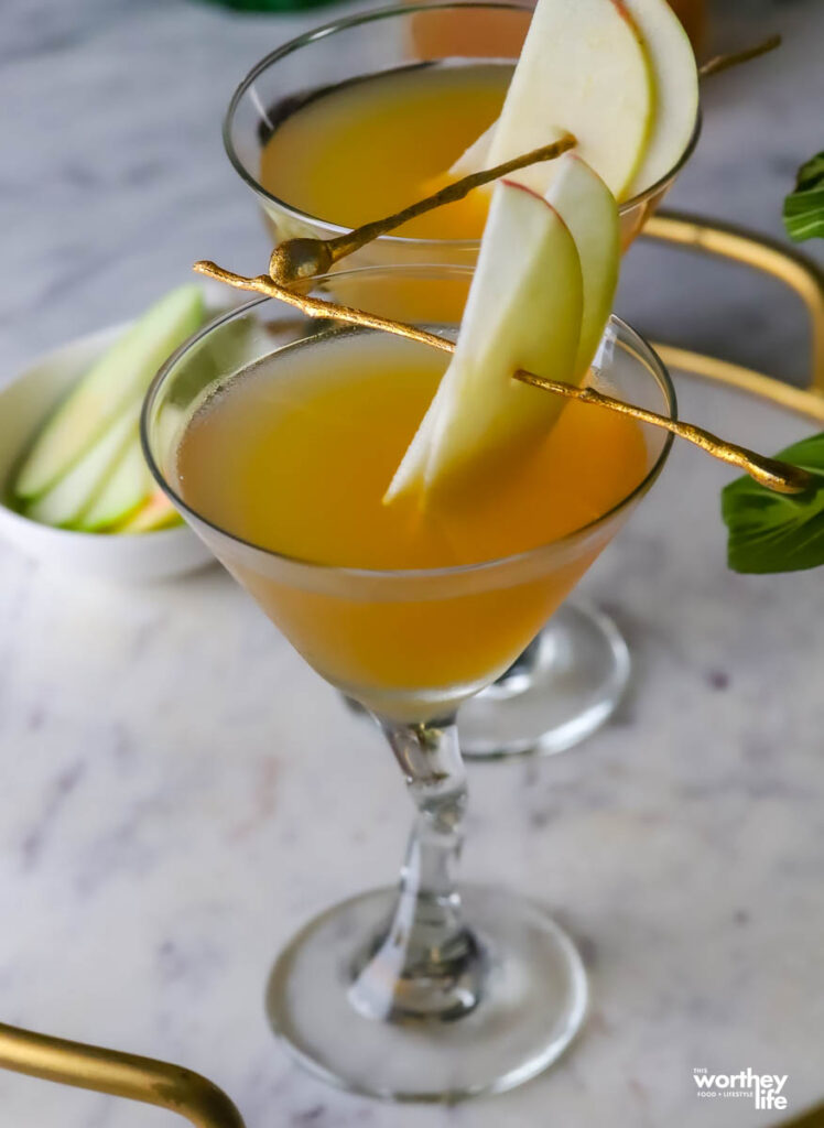 fall cocktail in martini glass with a slice of apple