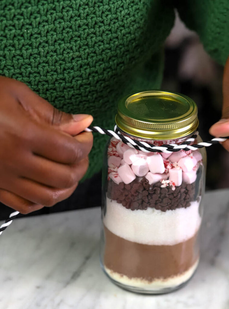 woman assembling a hot cocoa mix in a jar