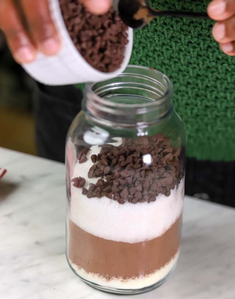 woman putting together a hot cocoa mix in a jar