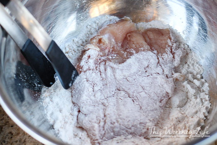 how to fry chicken- dredging the chicken breasts through the batter