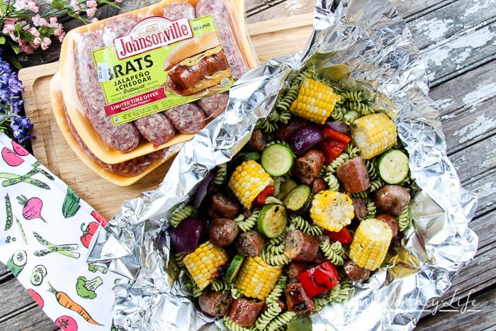 We're celebrating #bratsgiving with a fun twist on the classic crab + shrimp boil foil packets recipe by using pasta with herbs, bratwurst, and fresh veggies.