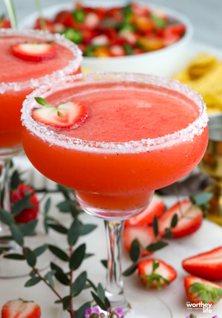 a strawberry margarita in a margarita glass with a salted rim