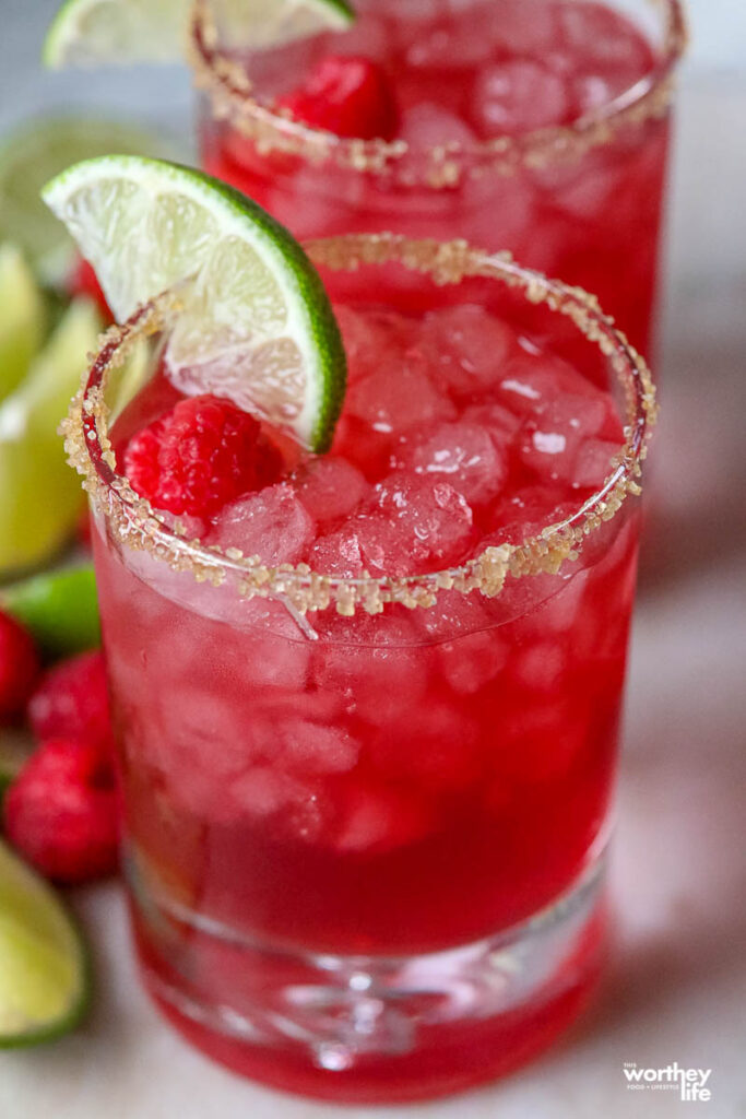 raspberry margarita in a glass with wedge of lime