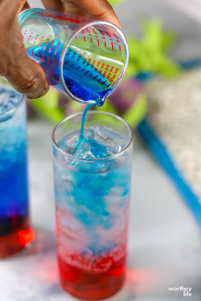 pouring blue syrup in glass with lemon lime soda