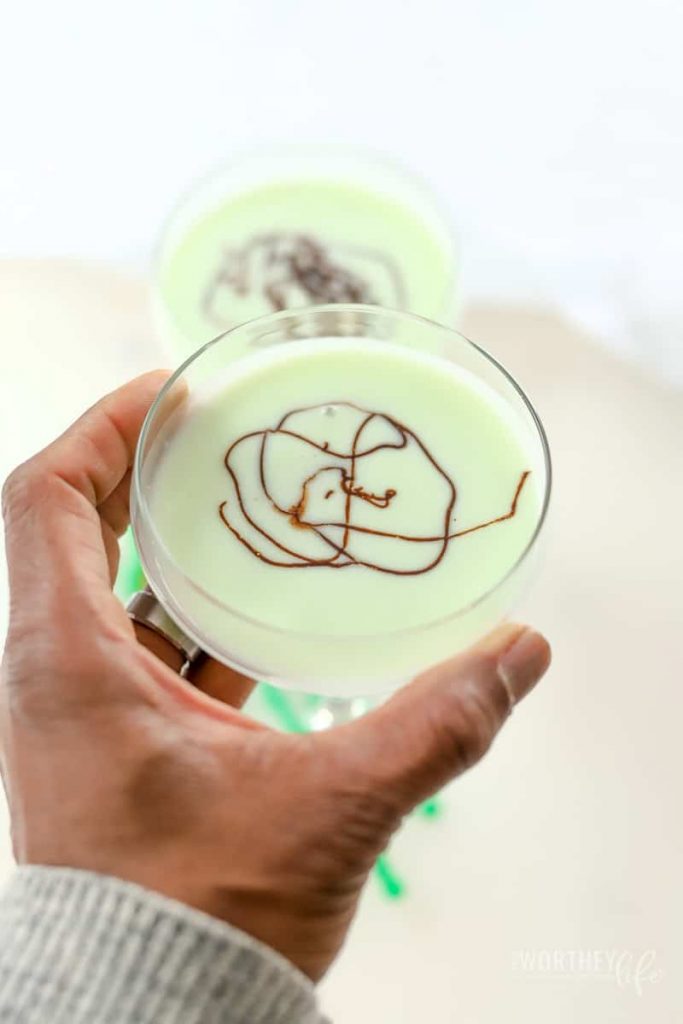 man's hands on a St. Germain Grasshopper in a tall cocktail glass