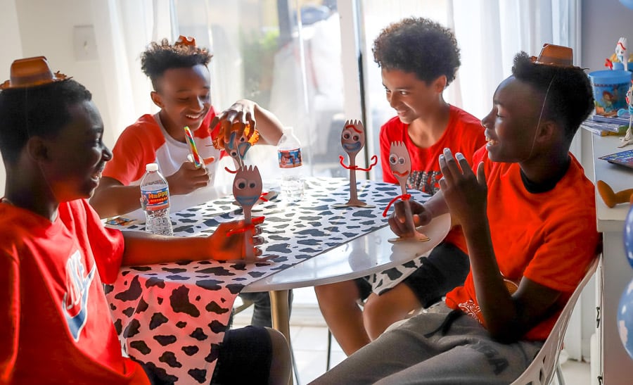 four black boys at a toy story party laughing and having a good time