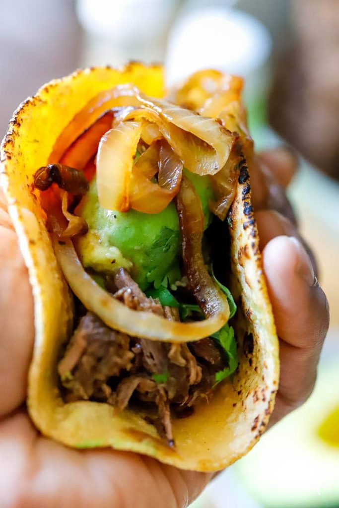 man's hand holding a beef soft taco