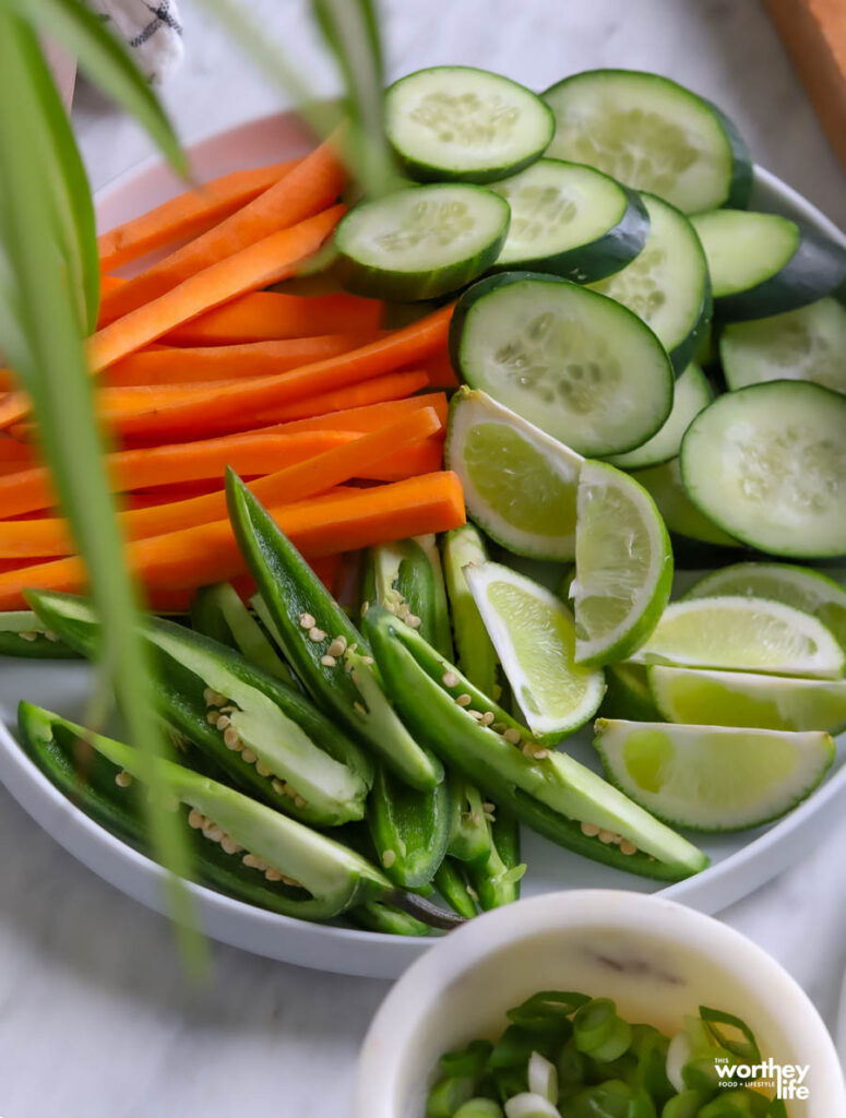 a white plate with an assortment of vegetables and lime wedges for serving with chicken wings.