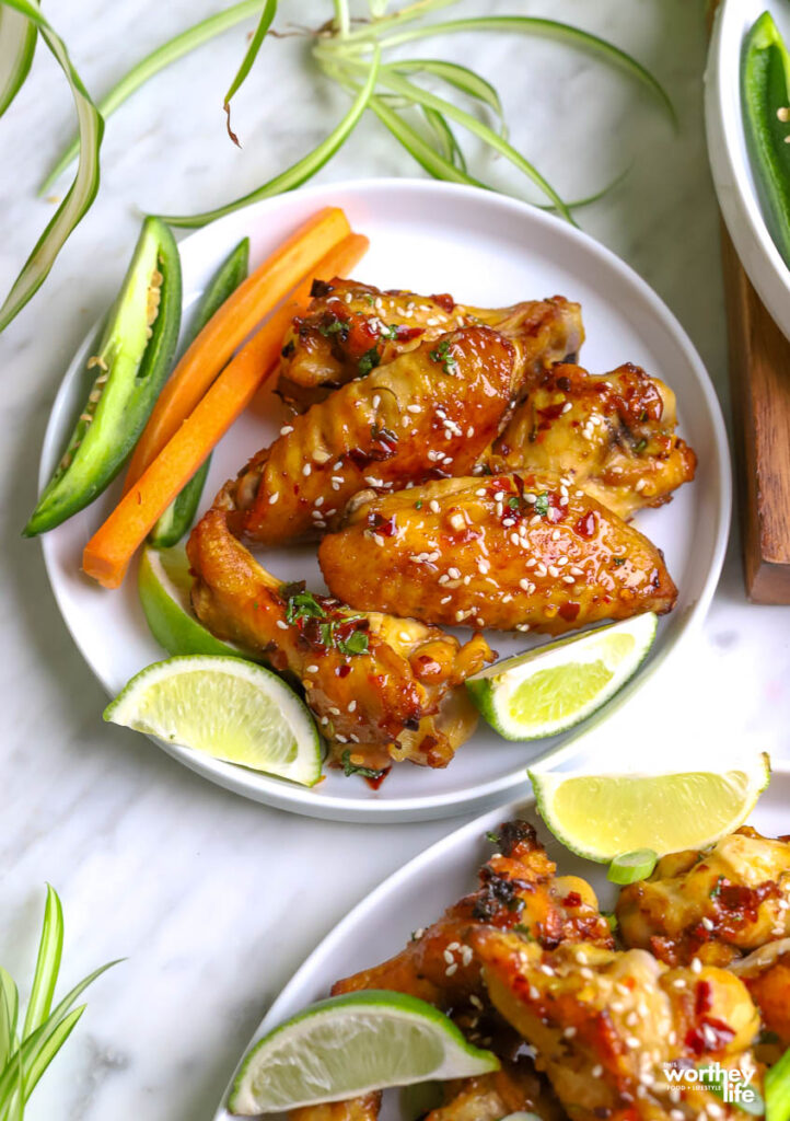 a small white plate with Thai chicken wings and garnishes. 