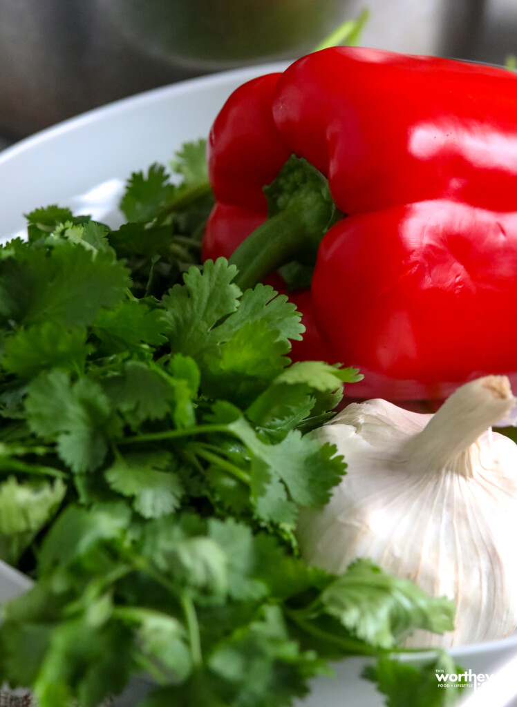 fresh cilantro, red pepper and garlic on white plate