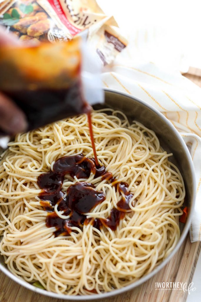 man pouring chicken stir fry marinade over pasta in pan