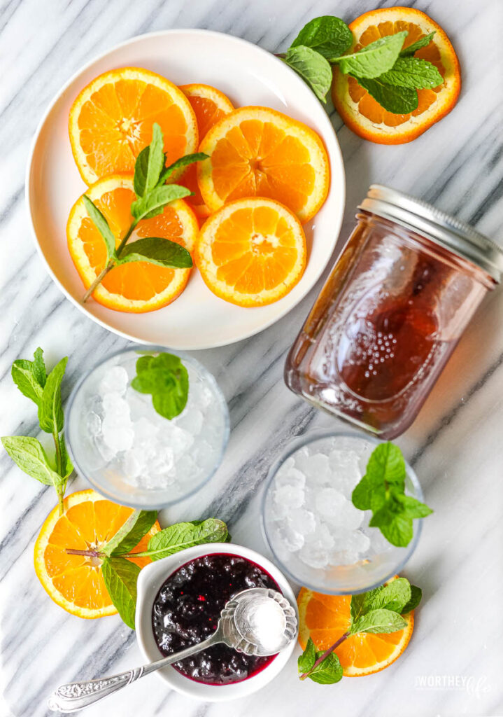 Blueberry Smash Syrup with orange slices on a white place and fresh mint leaves. 