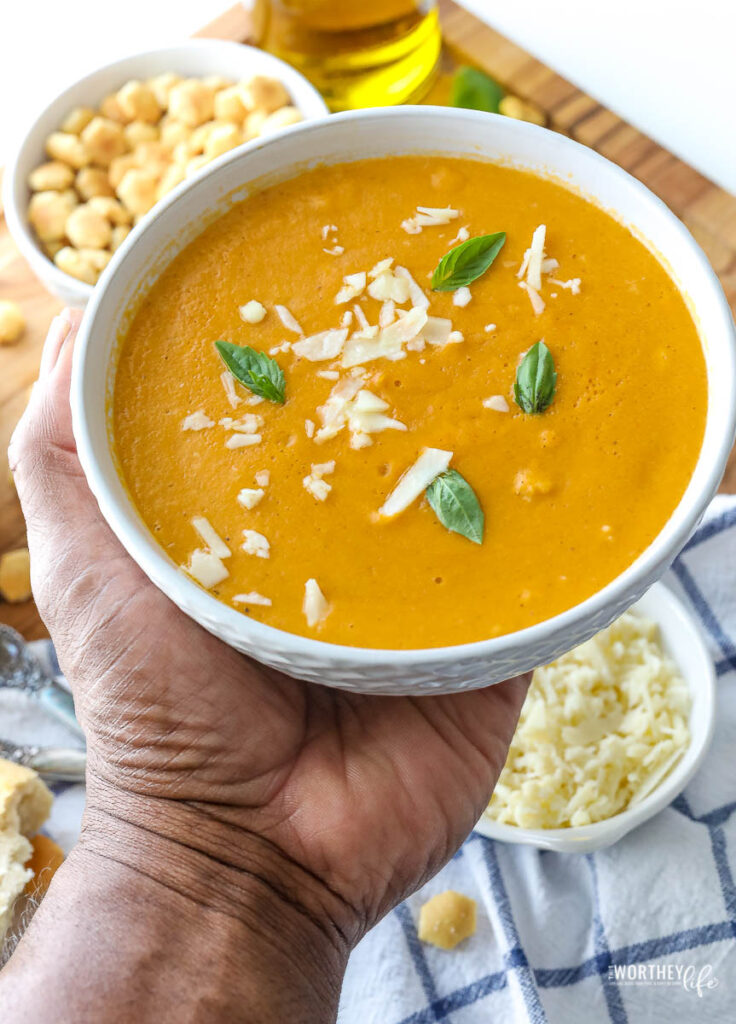 black man holding crab bisque in a bowl