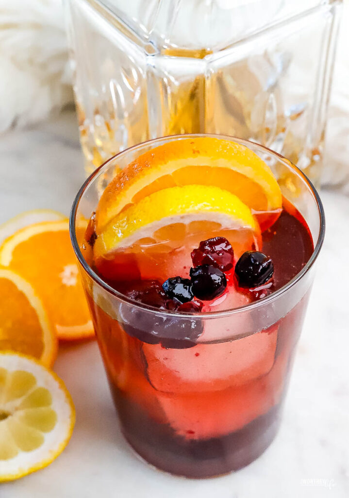 a cocktail served in a glass topped with a fruit syrup