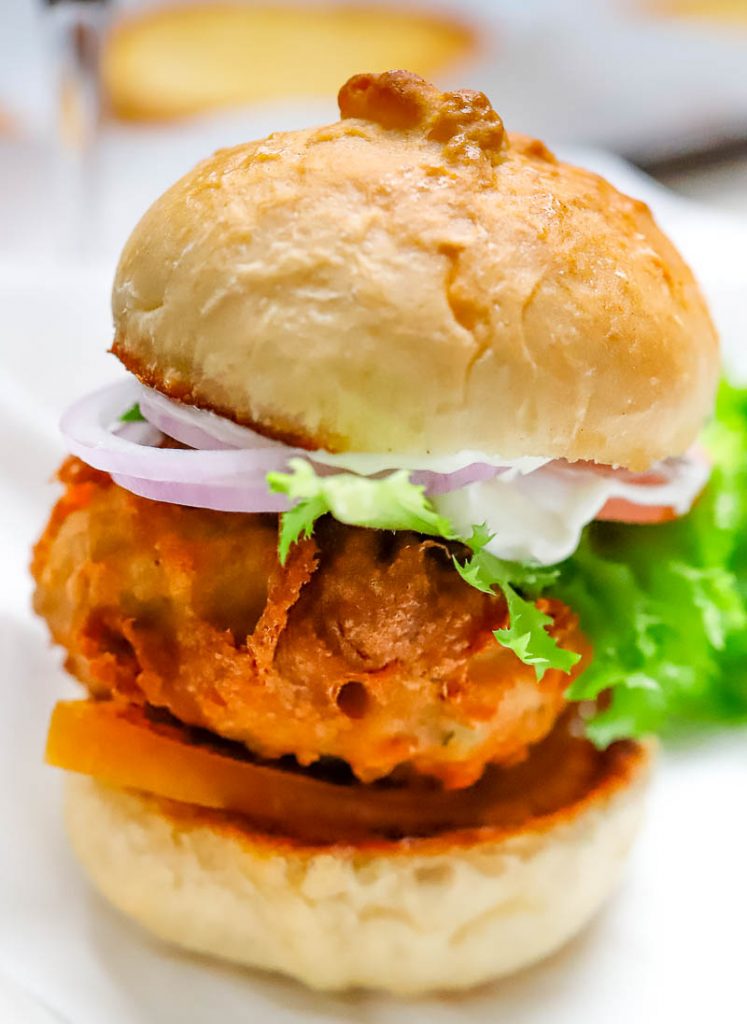 photo of a deep fried burger on a bun with lettuce and tomatoes