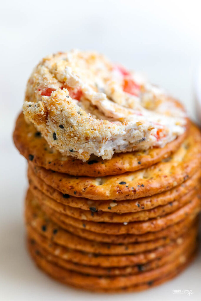 a stack of crackers with the top cracker topped with a smeared cheese ball