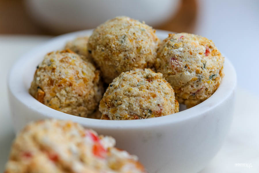 a white stone bowl filled with mini cheese ball rolled in cracker crumbles