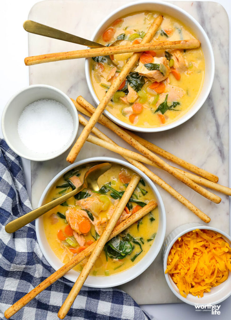 two bowls of spinach salmon soupon a white background