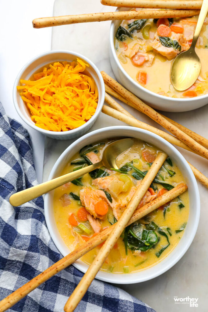 white porcelain bowls with salmon soup and breadsticks