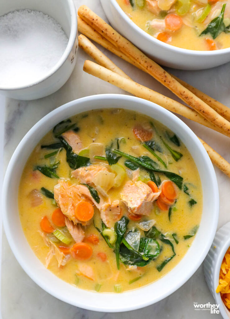 white bowl filled with salmon soup and crispy breadsticks 