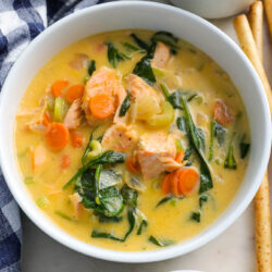 salmon soup in a white bowl with checkered cloth napkin