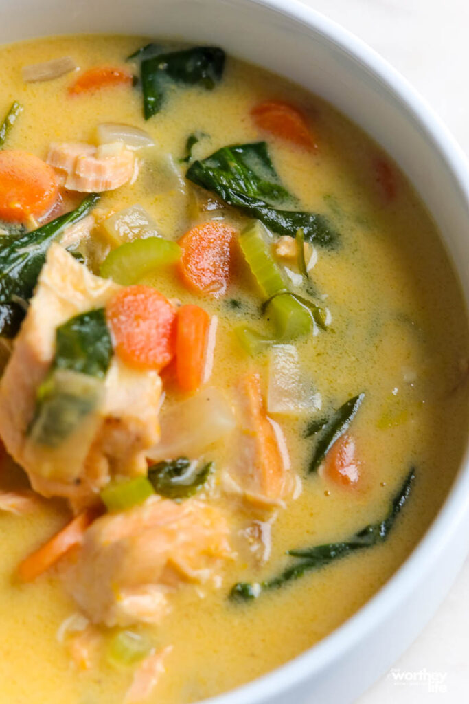 creamy spinach salmon soup in a white bowl close up