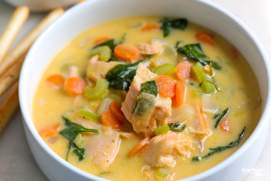 a white bowl filled with salmon and spinach soup