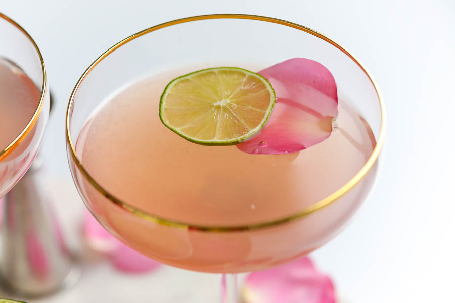close up of a gold rimmed glass filled with a pink vodka cocktail