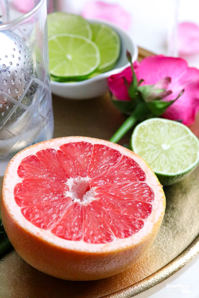 half of a sliced lime and grapefruit. a pink rose and lime slices