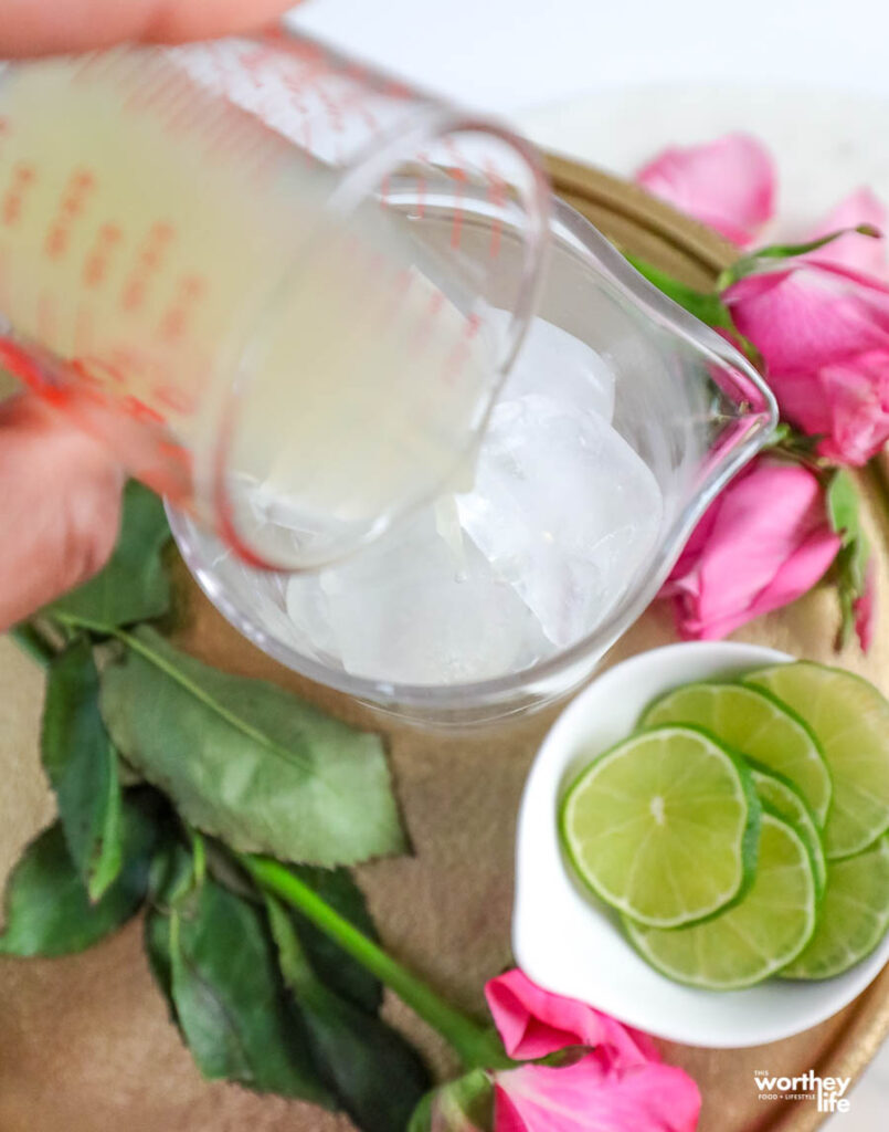 pouring fresh lime juice into a cocktail mixing glass filled with ice