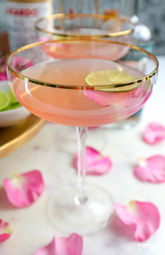 pink vodka drink in a tall glass with pink flower petals