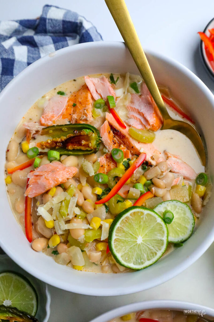 bowl of white chili salmon with fresh veggies and lime