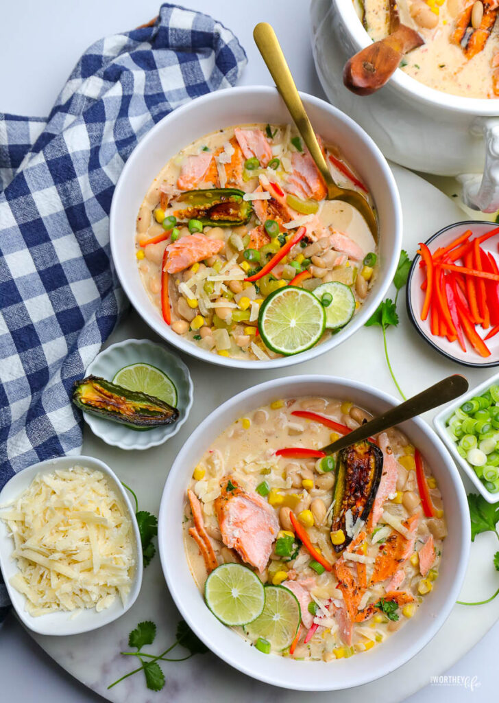 two white bowls of white chili salmon on white background with blue napkin