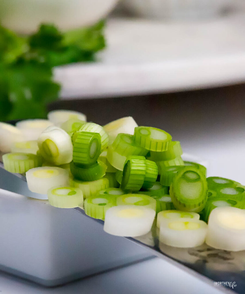 a sharp chef's knife turned sideways holding sliced green onions