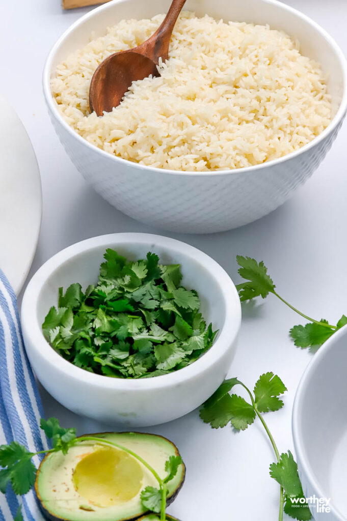 two white bowls with white rice and the other bowl filled with fresh cilantro