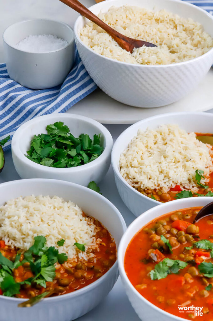 multiple white bowls filled with pigeon pea stew and rice