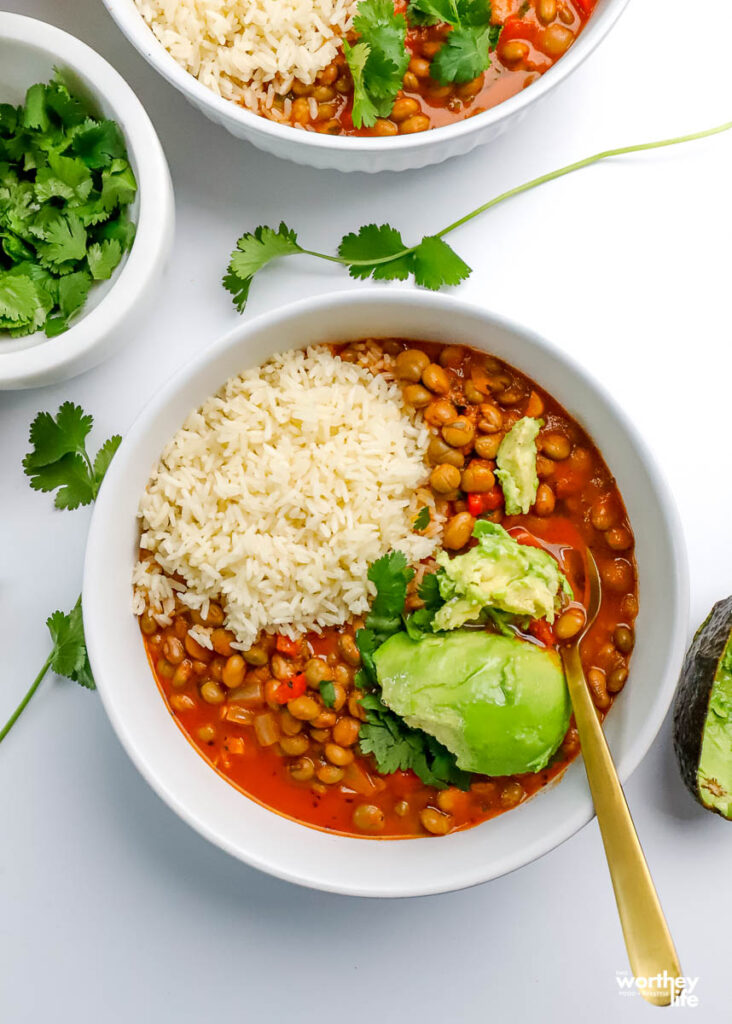 a serving bowl of pigeon peas soup served with white rice and avocado