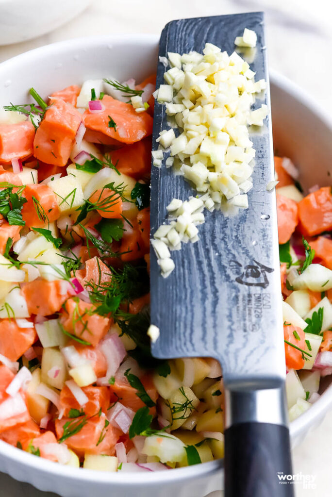 a white mixing bowl filled prepared ceviche and garlic