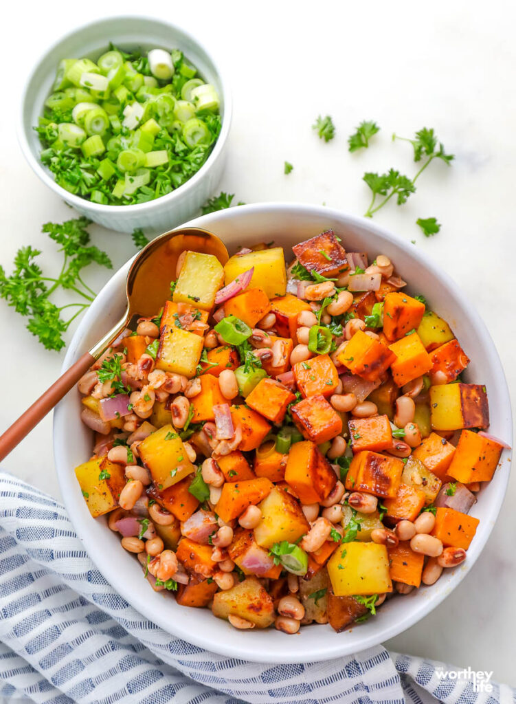 diced sweet potatoes mixed with black-eyed peas with fresh herbs in a white serving bowl