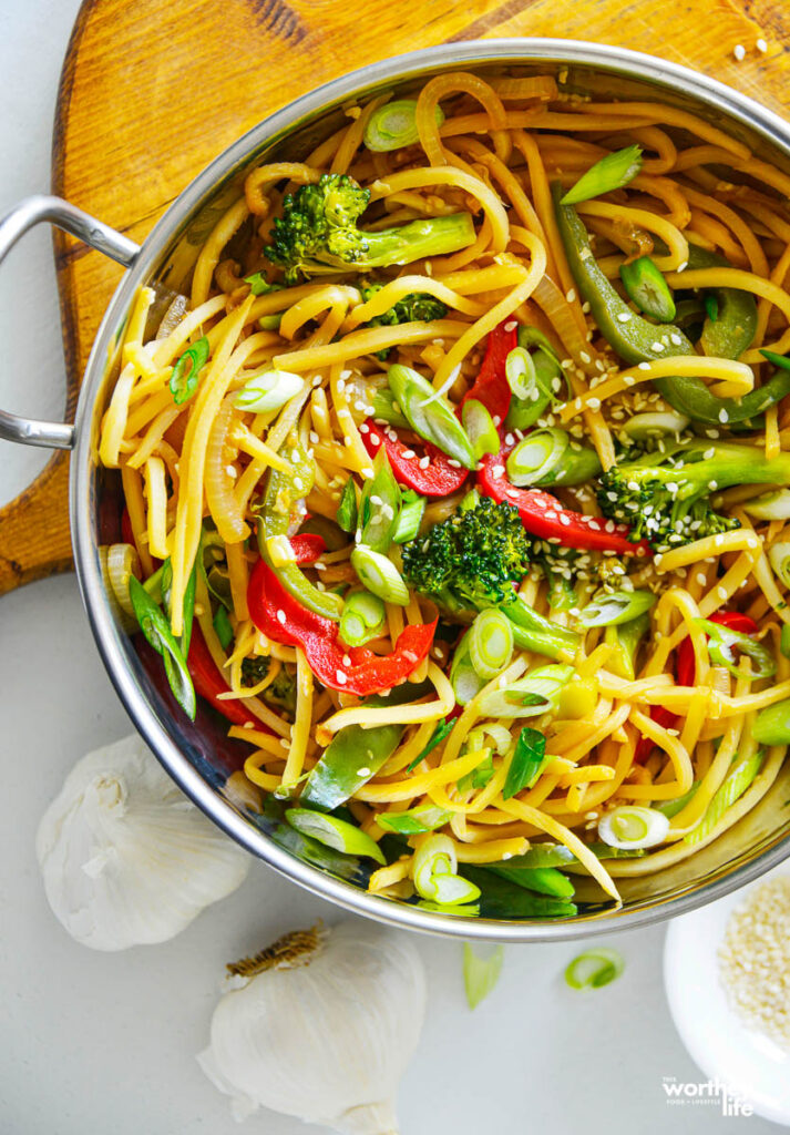 lo mein recipe in a skillet on a board