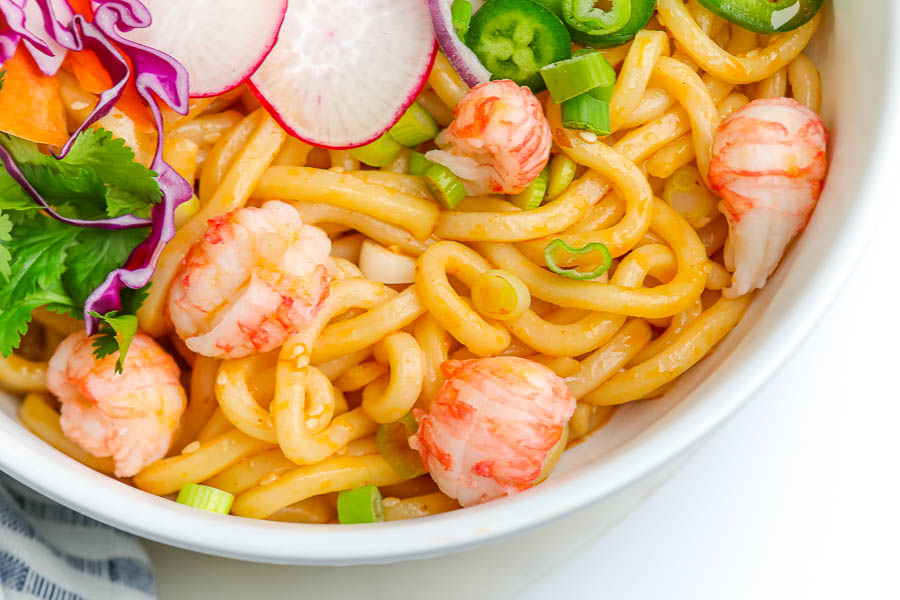 asian noodles in a white bowl with slices of radish and red cabbage