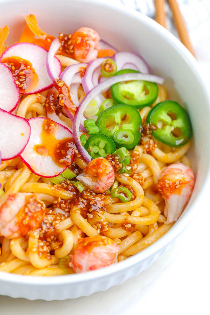 soba noodle salad in a white bowl with fresh vegetable toppings