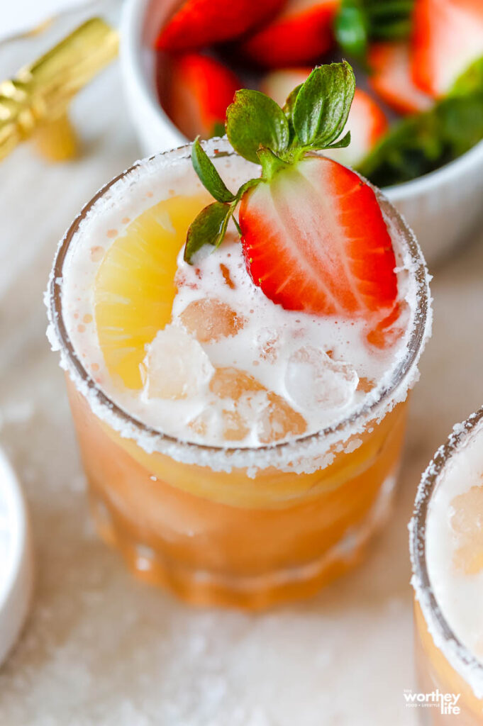 strawberry and pineapple cocktail in a serving glass topped with fruit