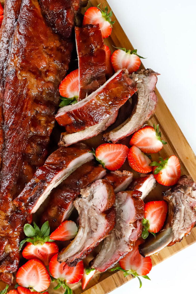 baby back ribs on cutting board with slices of strawberries
