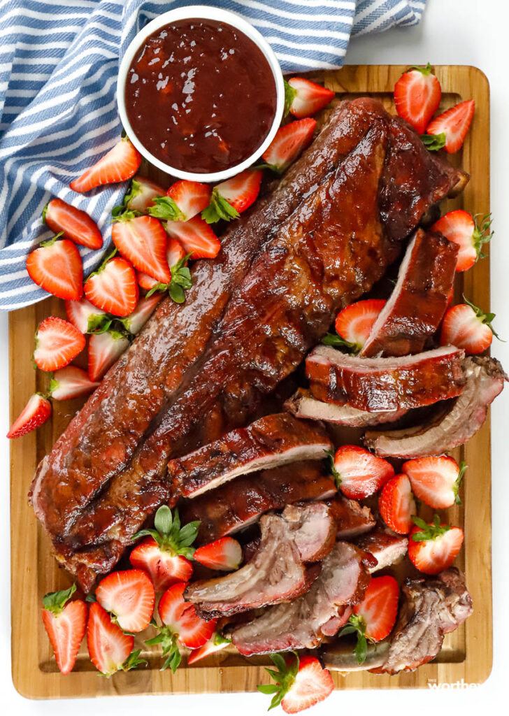 barbecued ribs and strawberry on a cutting board