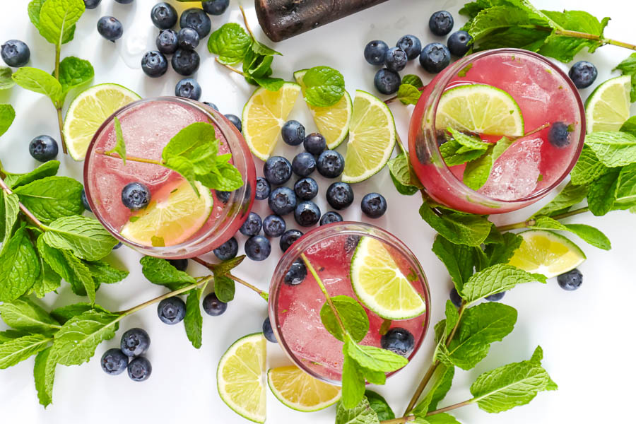 three glasses of mint mojito on a white background with fresh fruit