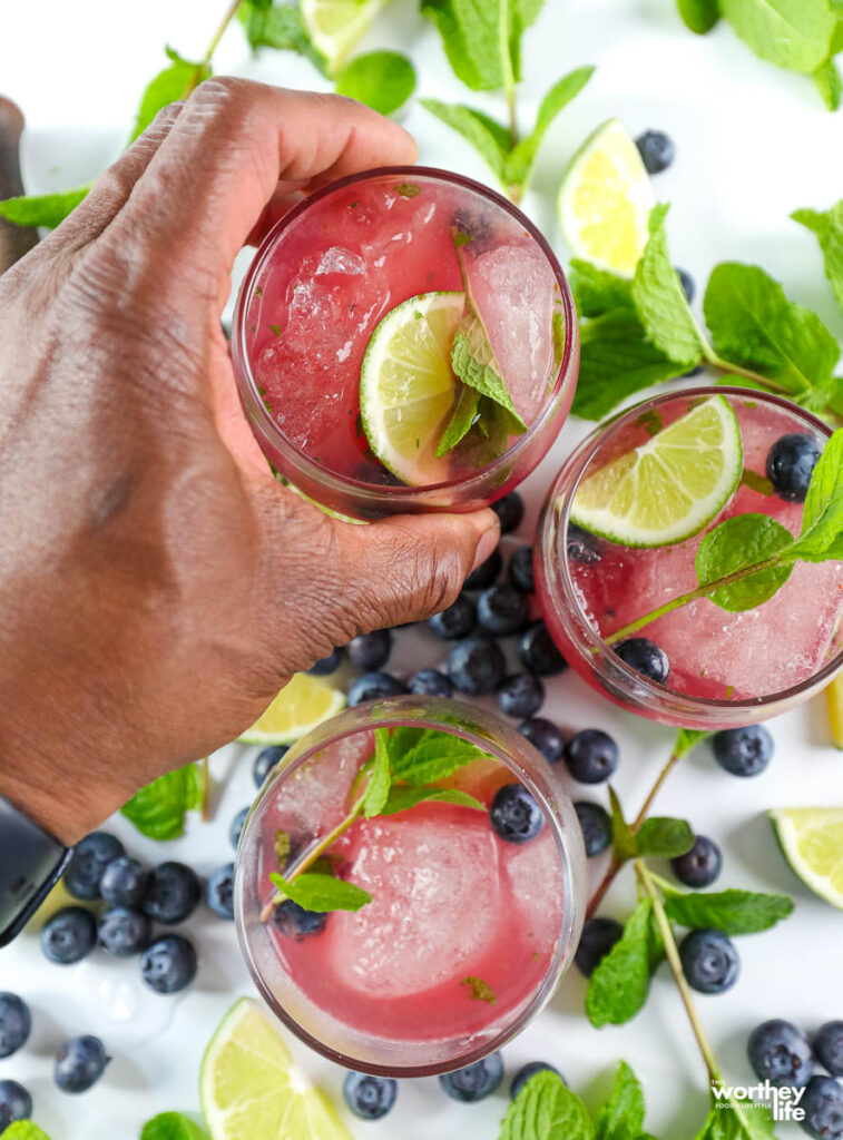 black hand grabbing a mint mojito cocktail