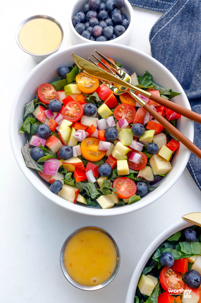 chopped super green salad in a white bowl with a fork and knife