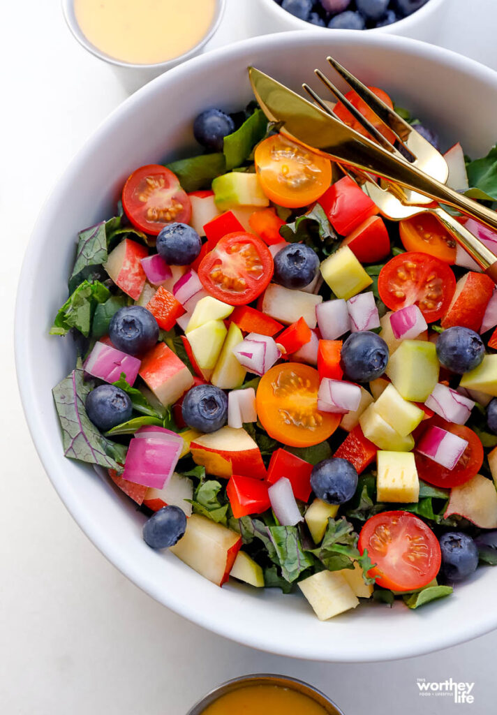 chopped kale salad in a white bowl with a fork and knife